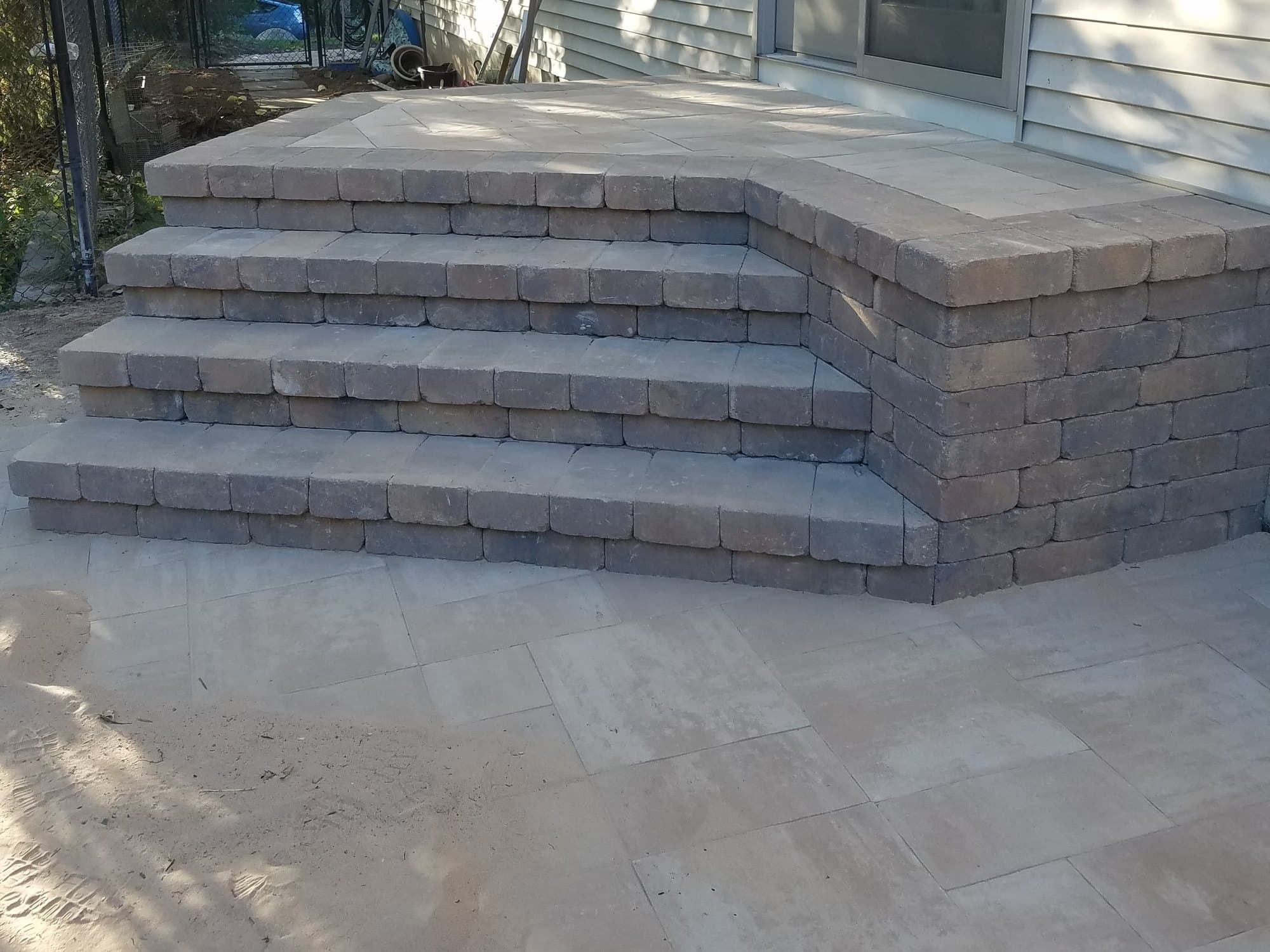 Paver stoop and landing with wrapped steps and a bullnose edge beside a house wall
