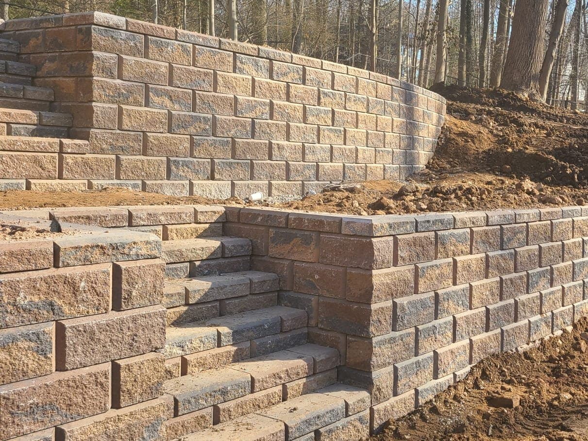 Steps cut between two tiers of tan block wall, close on the corner where the tiers meet
